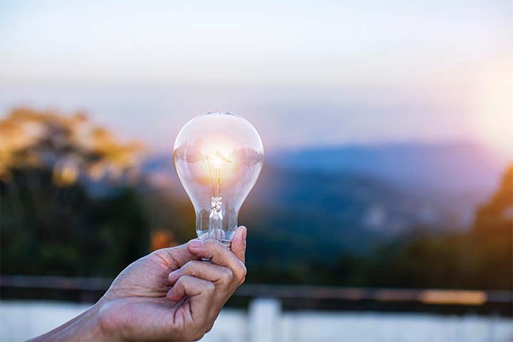hand holding light bulb against nature, icons energy sources for renewable,